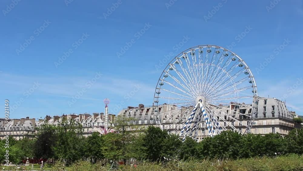View of ferris wheel, trees and buildings at Jardin des Tuileries in Paris.