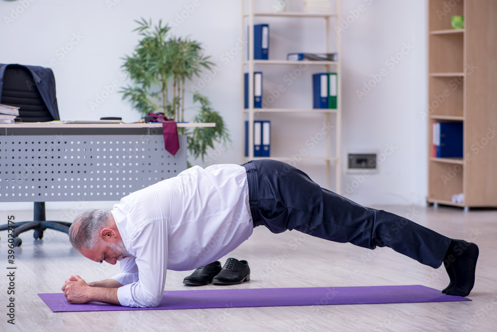 Aged male employee doing physical exercises during break