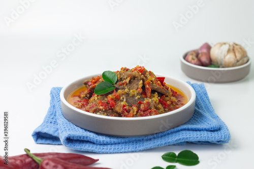 Dendeng Balado, Indonesian traditional beef cuisine from Padang, West Sumatra with slices beef cooked with some spices and a lot of chilies. Served on ceramic plate and isolated white background. 
