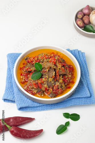 Dendeng Balado, Indonesian traditional beef cuisine from Padang, West Sumatra with slices beef cooked with some spices and a lot of chilies. Served on ceramic plate and isolated white background. 