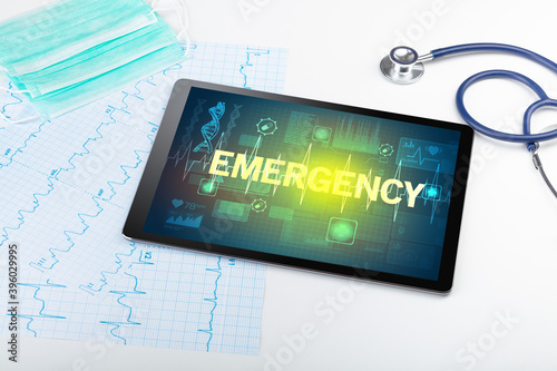 Tablet pc and medical stuff with EMERGENCY inscription, prevention concept