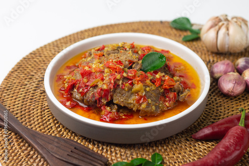 Dendeng Balado, Indonesian traditional beef cuisine from Padang, West Sumatra with slices beef cooked with some spices and a lot of chilies. served on ceramic plate and isolated white background. 