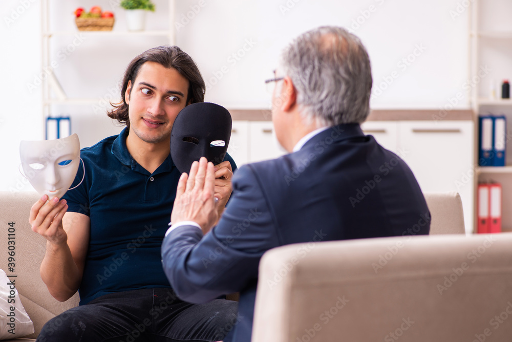 Young man wearing masks during psychotherapy session Young man wearing masks during psychotherapy session
