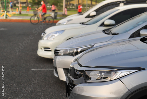 Closeup of front side of gray car with  other cars parking in outdoor parking area in the evening.  © Amphon