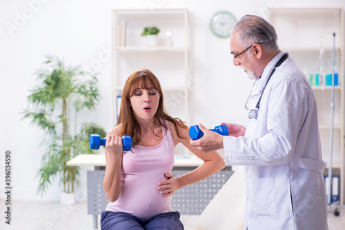 Young pregnant woman visiting old male doctor gynecologist