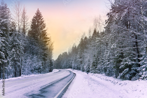 Snowy road in winter forest. Beautiful frosty white landscape at dawn.
