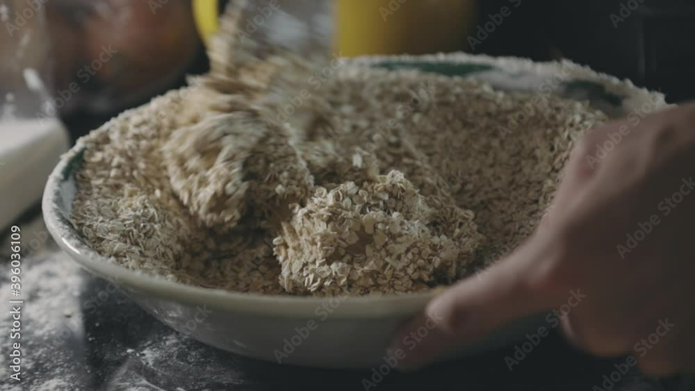 Person Mixing Batter With Rolled Oats Using A Wooden Spoon. - clsoe up shot Person Mixing Batter With Rolled Oats Using A Wooden Spoon. - clsoe up shot