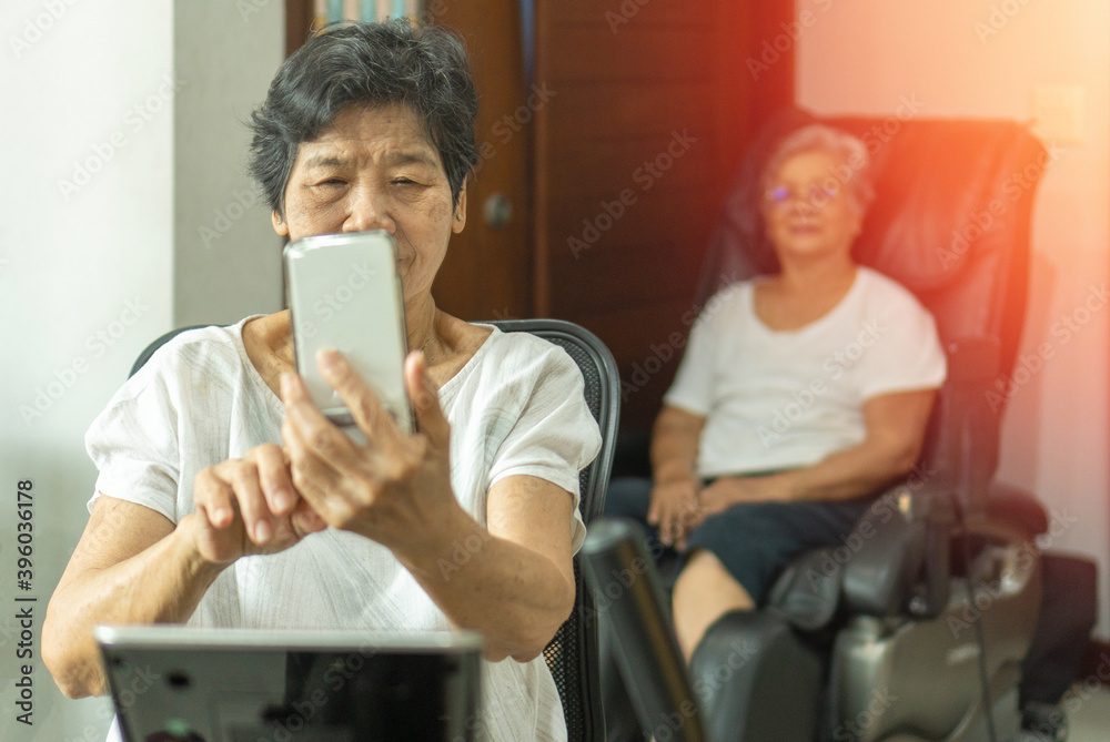 Φωτογραφία Active Asia senior old woman people training exercise on stationary bike for fit healthy  and  using smartphone to chat and  connect with aging society at home gym