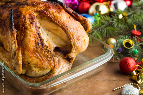 Roasted turkey in glass ovenware on the wooden table with christmas ornaments.Conceptual image of Christmas or New Year. photo