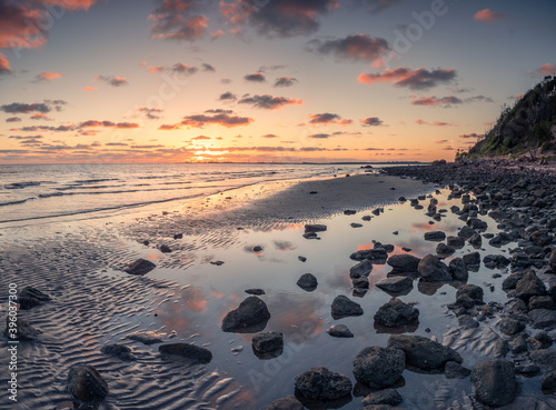 Beautiful Seaside Sunrise with Cloud Reflections and Rocks