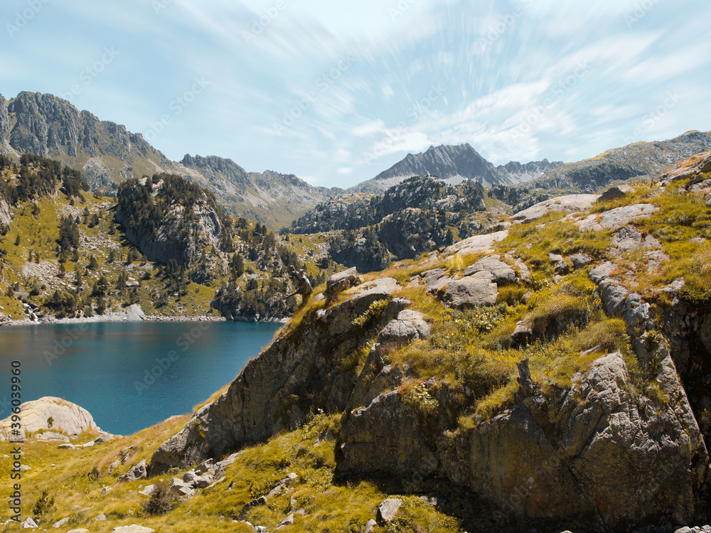 Lake and mountains with blue sky and clouds in long exposure in the Aran Valley. Scenic nature concept. 