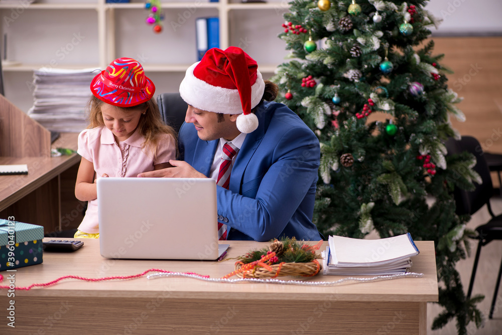 Young male employee celebrating Christmas at workplace with his Young male employee celebrating Christmas at workplace with his
