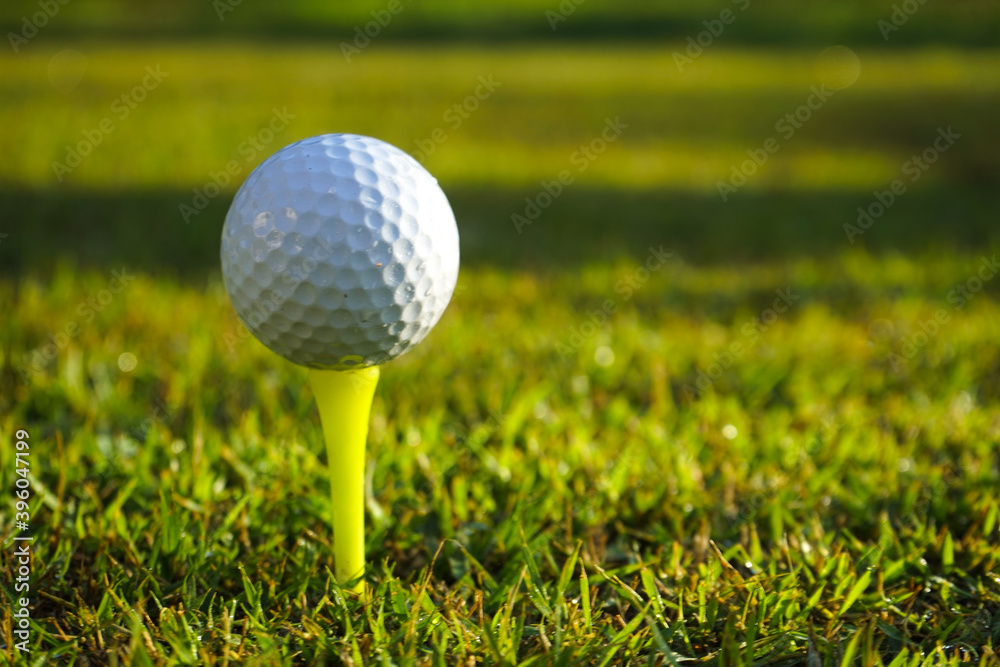 Golf ball on tee in beautiful golf course at sunset background Golf ball on tee in beautiful golf course at sunset background