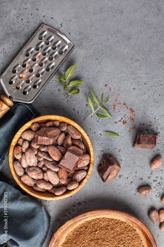 Cocoa beans, cocoa powder, raw chocolate on a gray background. The concept of healthy eating. Copy space.