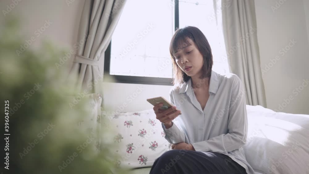 Asian woman using smartphone sitting down on couch at home living room, online dating application, sending email messaging online communications, house wife comfortable simple living, shopping online Asian woman using smartphone sitting down on couch at home living room, online dating application, sending email messaging online communications, house wife comfortable simple living, shopping online
