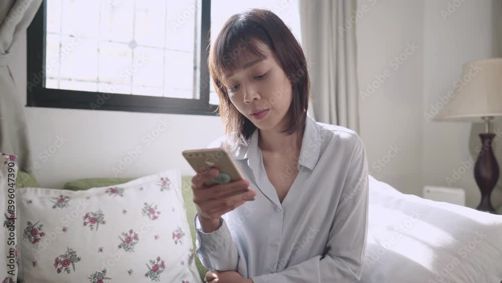 Asian short hair woman holding smartphone with reading on online information at living room, internet knowledges accessibility, worldwide data, distant communication, relaxing weekend activity at home Asian short hair woman holding smartphone with reading on online information at living room, internet knowledges accessibility, worldwide data, distant communication, relaxing weekend activity at home