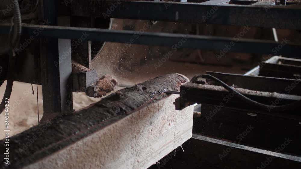 Sawing log into boards with machine tool in woodwork shop Sawing log into boards with machine tool in woodwork shop