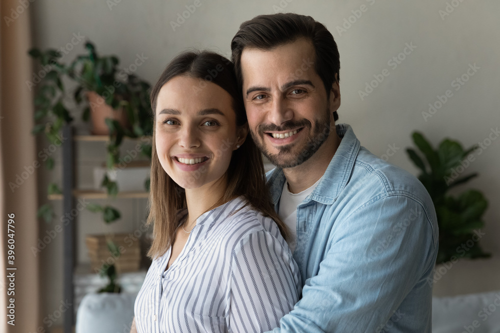 Family portrait of happy young Caucasian couple stand hugging cuddling show love and care. Smiling millennial man and woman spouses enjoy tender close romantic moment. Good relations concept. Family portrait of happy young Caucasian couple stand hugging cuddling show love and care. Smiling millennial man and woman spouses enjoy tender close romantic moment. Good relations concept.