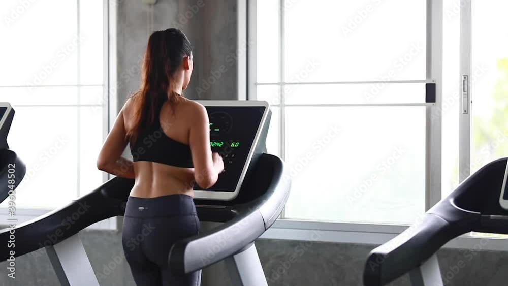 Young people running on a treadmill in health club. Side view.