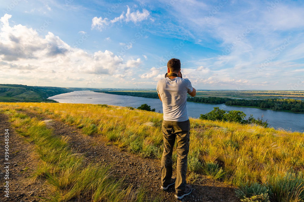 Back view of a photographer taking pictures of river landscape Back view of a photographer taking pictures of river landscape
