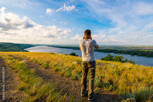 Obraz na płótnie Back view of a photographer taking pictures of river landscape w salonie
