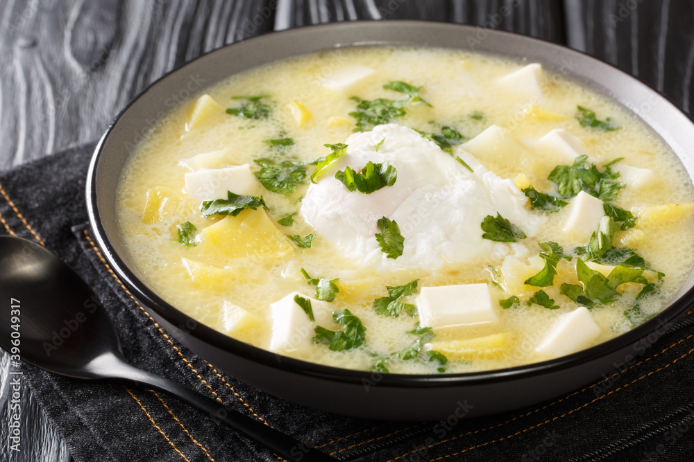 Delicious latino american chicken broth with potatoes, eggs, white cheese and cilantro close-up in a bowl on the table. horizontal