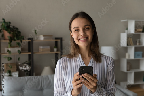 Portrait of smiling young Caucasian woman browsing surfing wireless internet on smartphone gadget. Happy millennial female client or customer use modern cellphone device. Technology concept.