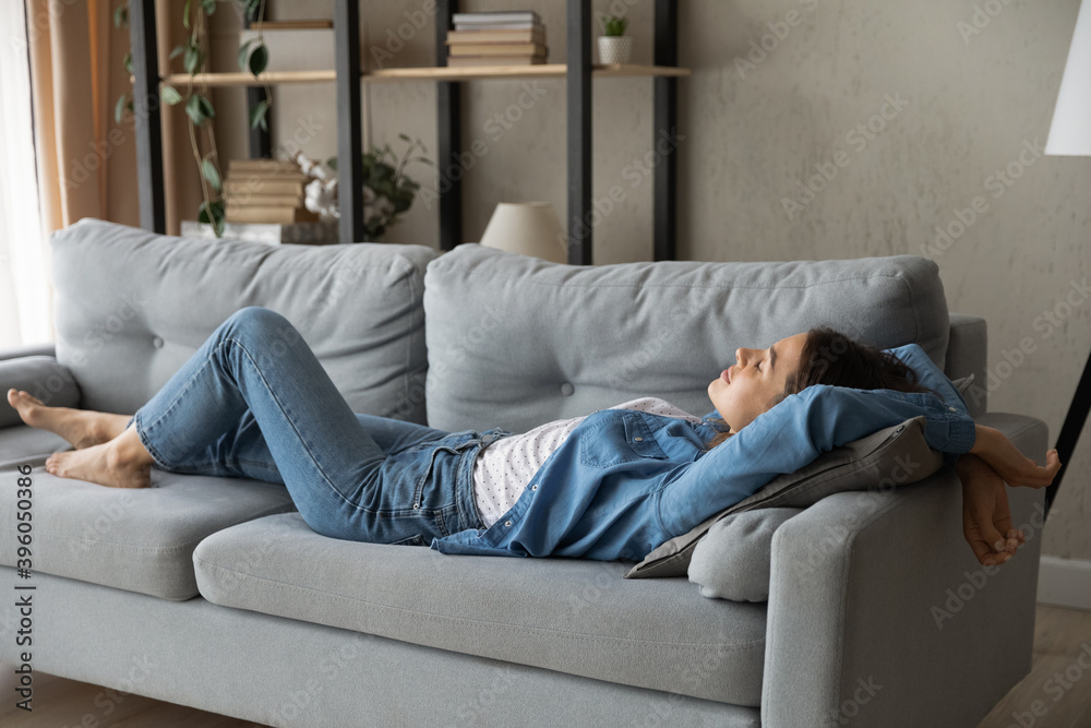 Φωτογραφία Exhausted young Caucasian woman lying relaxing on sofa in living room sleep or take nap at home