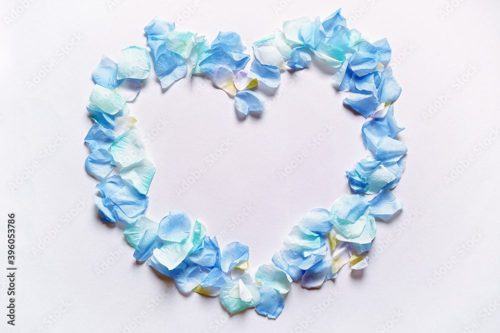 Obraz premium 造花の青い花びらでかたどったハートのフレーム。白いコピースペース。平置きの俯瞰撮影。白バック。