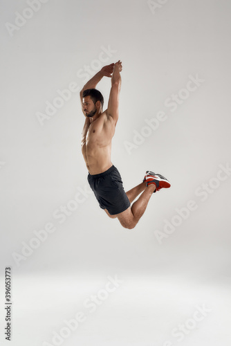 Young male athlete in high sideway jump with raised hands