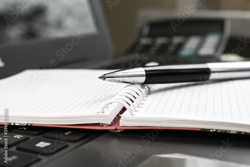 the pen and Notepad are on the laptop keyboard on the blurred background of the calculator. The concept of business and education