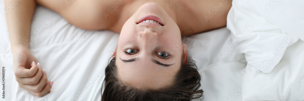 Smiling naked girl lies in comfortable soft bed. Girl woke up in good mood and smiling. Help defuse and release muscle clamps. Hypoallergenic bedding. Early awakening in apartment Smiling naked girl lies in comfortable soft bed. Girl woke up in good mood and smiling. Help defuse and release muscle clamps. Hypoallergenic bedding. Early awakening in apartment