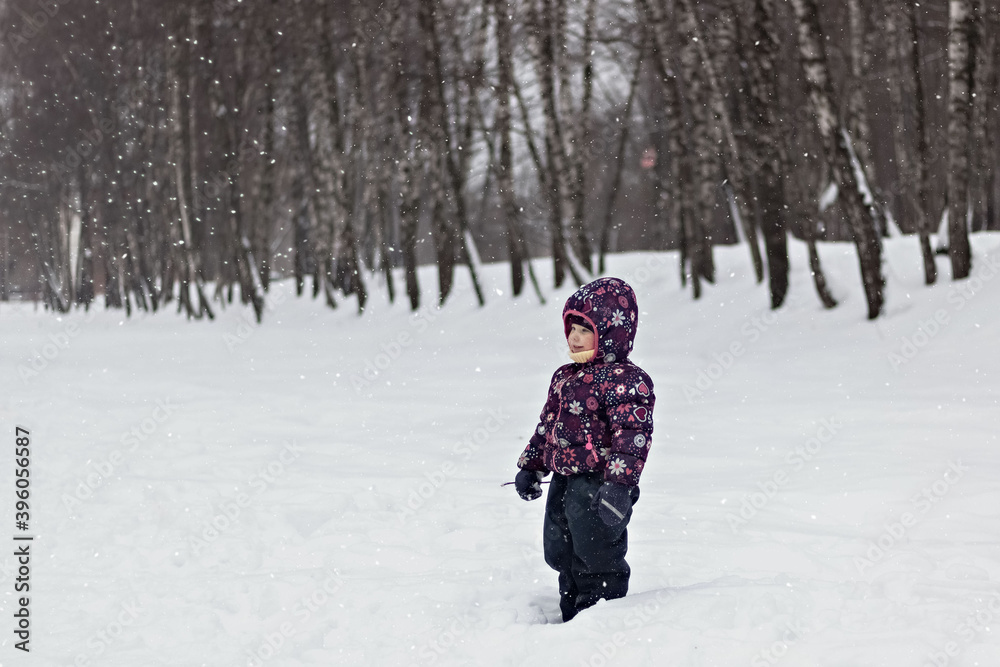 A little girl stands in a winter snow Park. Christmas holidays