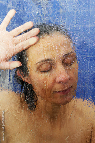 Retrato creativo de una mujer bajo la ducha con los ojos cerrados expresando calma y tranquilidad