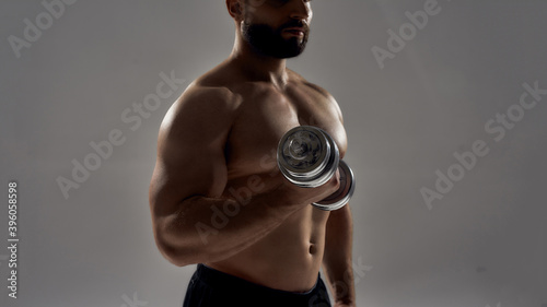 Blacked figure of young muscular athlete lifting dumbbell