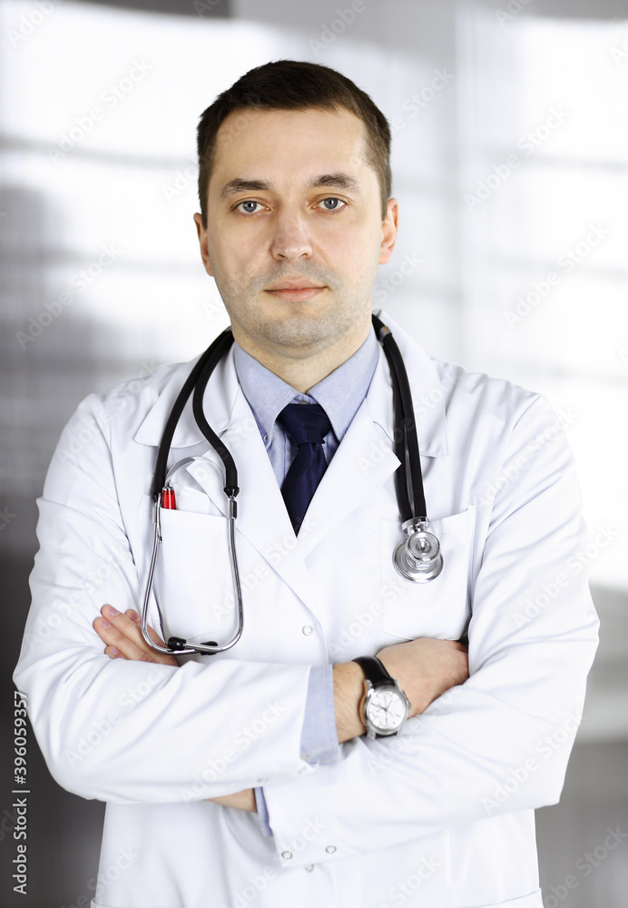 Professional doctor with a stethoscope is standing with crossed arms in a clinic. Perfect medical service in hospital. Medicine and healthcare concept Professional doctor with a stethoscope is standing with crossed arms in a clinic. Perfect medical service in hospital. Medicine and healthcare concept
