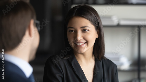 Nice to meet you. Glad mixed race businesswoman getting acquainted welcoming new staff member in office, smiling millennial indian female employee listening to experienced male colleague with interest