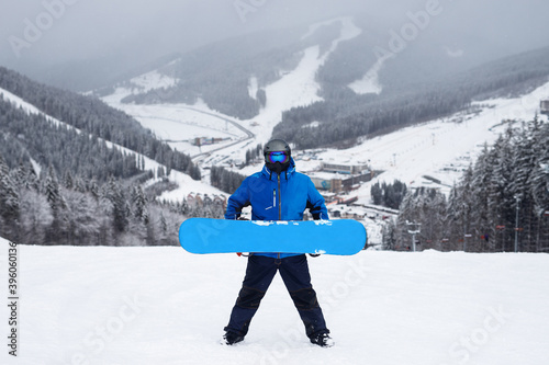 The guy hold in hand blue snowboard in winter