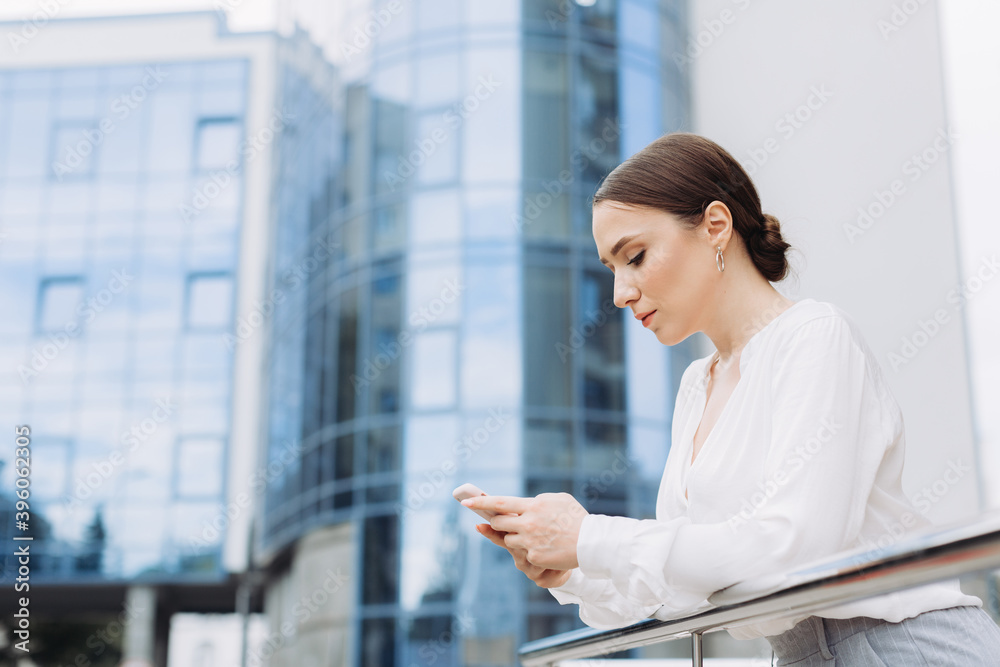 Business woman near the business center checks her smartphone Business woman near the business center checks her smartphone
