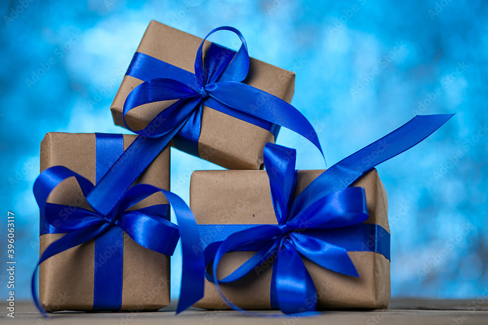 Christmas gift boxes with blue ribbons against blue lights garland and bokeh background. Holiday greeting card. Christmas gift boxes with blue ribbons against blue lights garland and bokeh background. Holiday greeting card.