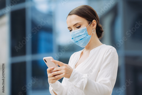 Young businesswoman wearing a medical mask stands near the office center.