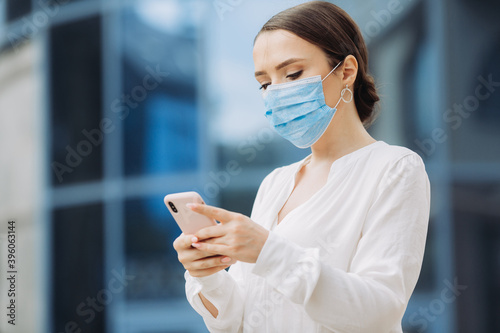 business woman in a protective mask checks her phone
