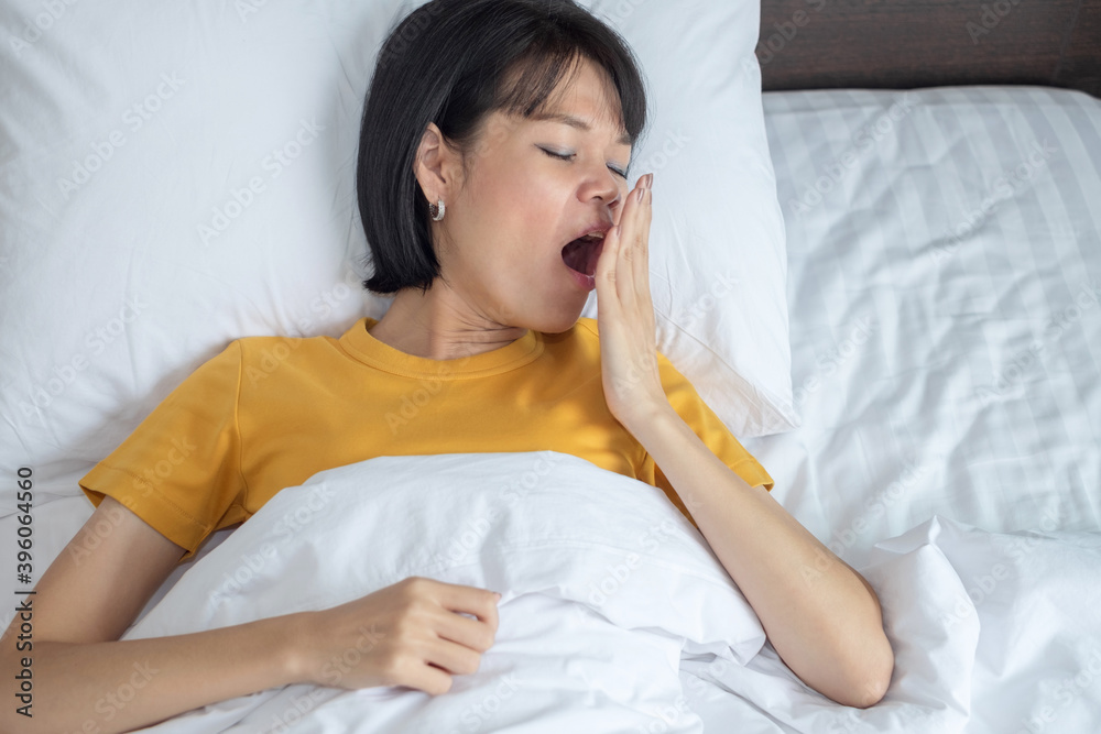 Top view of an Asian woman yawning Sleep in bed in bedroom Top view of an Asian woman yawning Sleep in bed in bedroom
