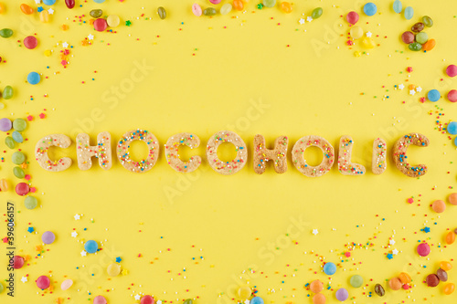 Chocoholic word made of sweet cookies decorated with colorful sprinkles and chocolate candies around