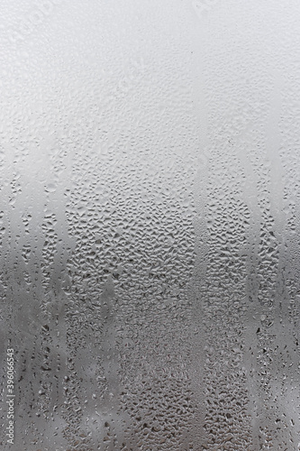 Close up water drop on grey background, misted glass with droplets of water draining down. Dripping Condensation