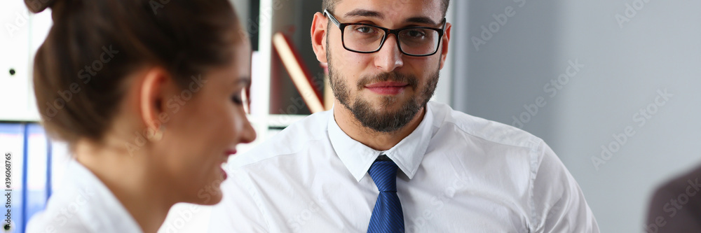 Cheerful young office worker sitting near his colleagues while and listening to useful information Cheerful young office worker sitting near his colleagues while and listening to useful information