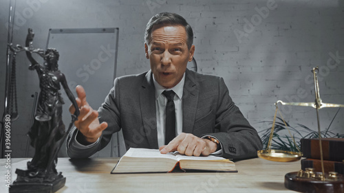 Cuadro en lienzo insurance agent pointing with finger at book near scales and statuette of justi