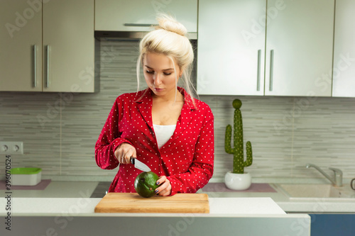 blonde vegan woman cuts avocado in kitchen