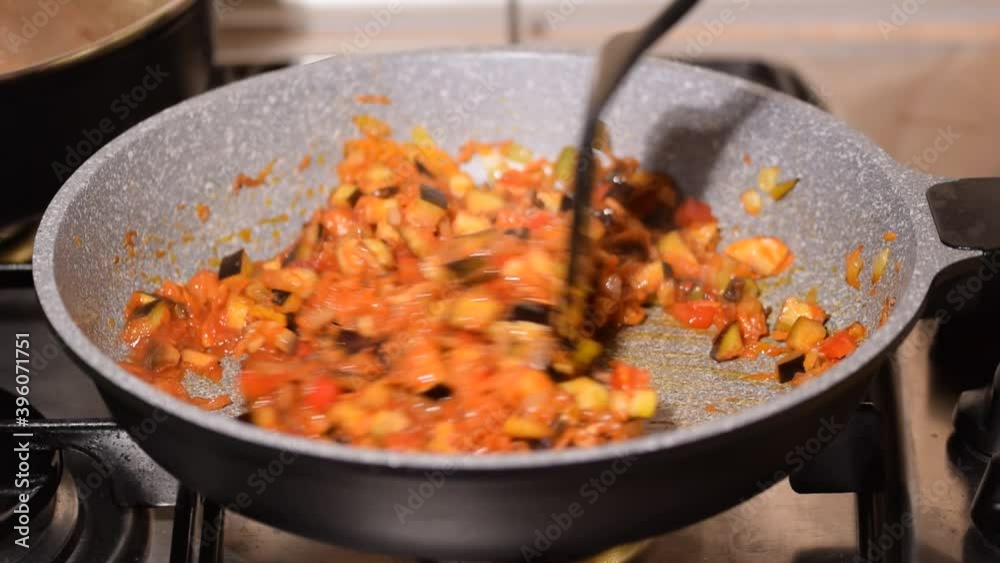 Close-up of a young woman cooking vegetables in a fry pan. Close-up of a young woman cooking vegetables in a fry pan.