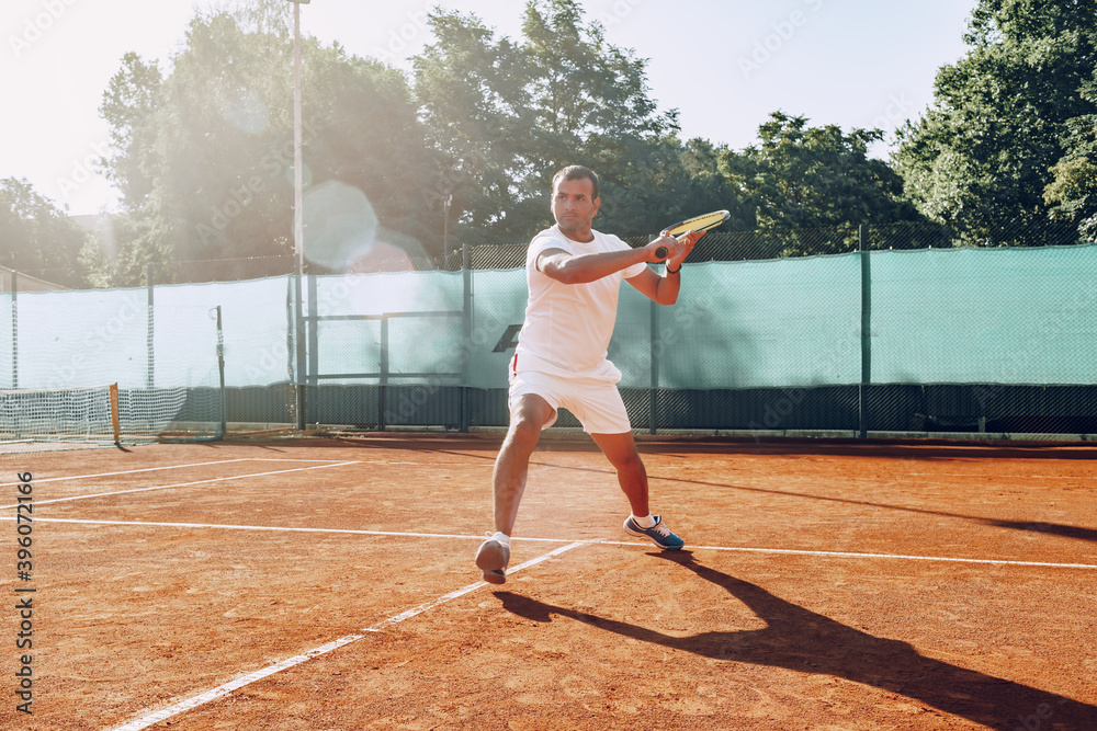 Fit man plays tennis on tennis field